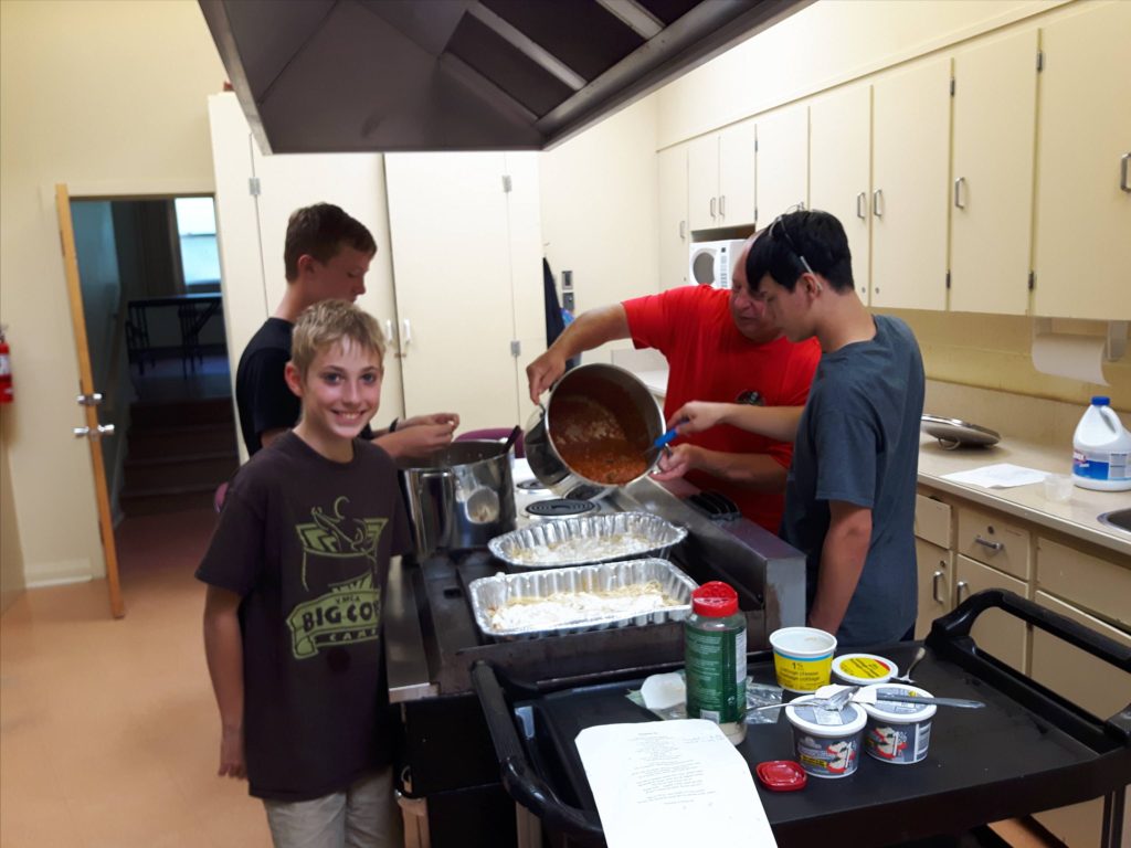 Scouts practicing their cooking skills by preparing a meal for ARK Outreach Centre.